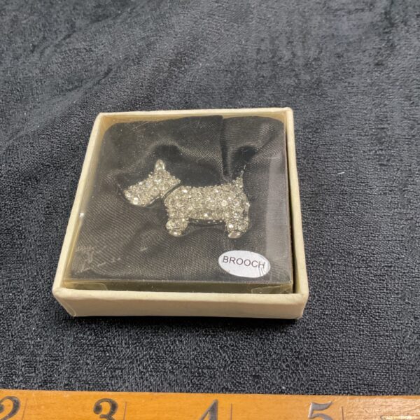 Vintage white stone Scottie dog brooch on display.
