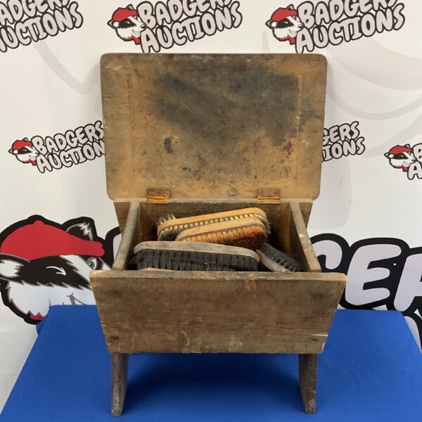 Vintage wooden shoe shine box with brushes inside.