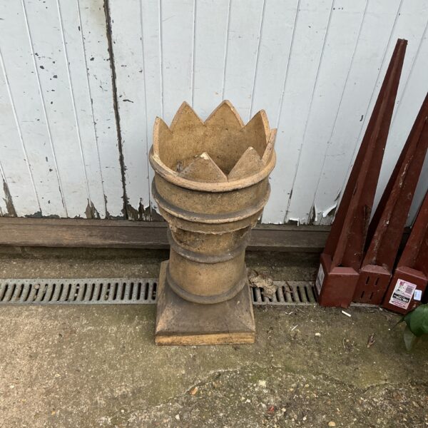 Vintage terracotta chimney pot in a garden setting.