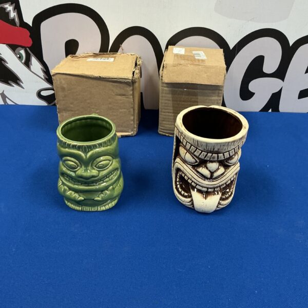 Pair of vintage ceramic tiki mugs with carved faces.