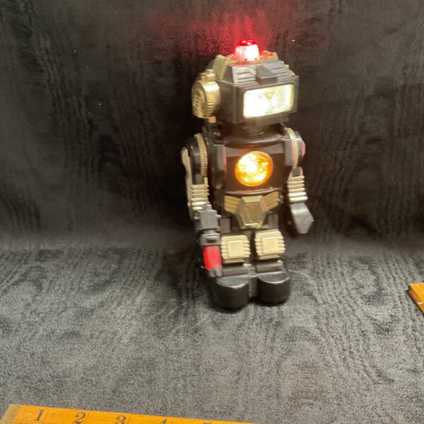 Front view of a vintage toy robot with red light.
