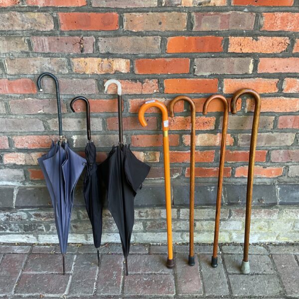 Vintage umbrellas and walking canes displayed on a brick surface.