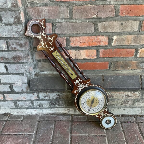 Vintage wall barometer clock with wooden case and detailed carving.