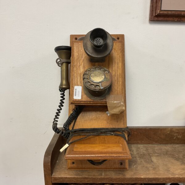 Side view of a vintage wall telephone with wooden backplate.