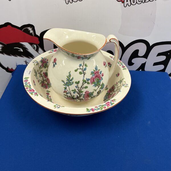 Vintage porcelain wash bowl and jug set with floral design.