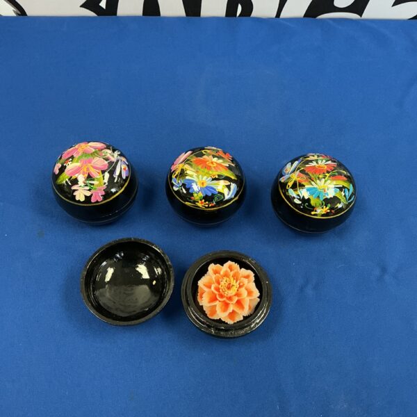 Vintage wax flower displayed in a decorative box with floral pattern.