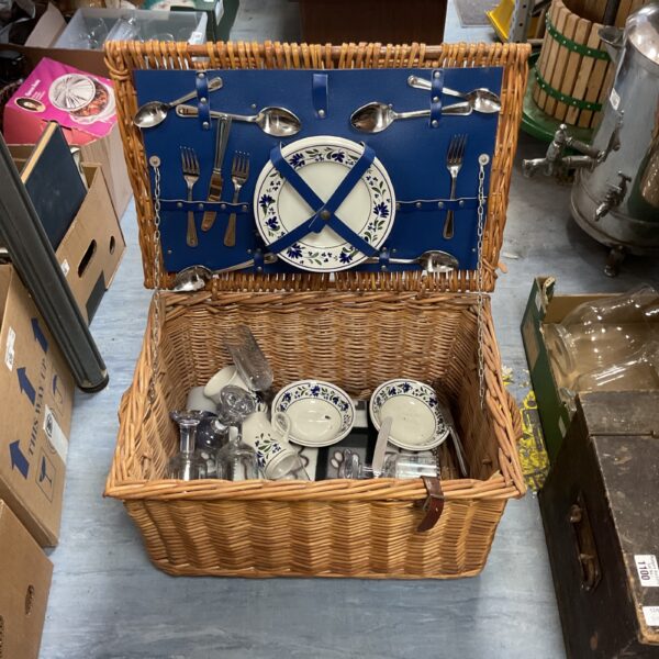 Vintage wicker picnic basket with complete dining service inside.