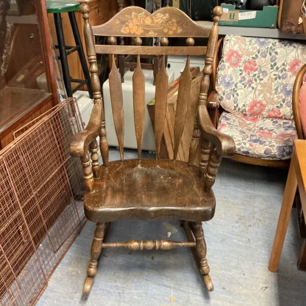 Vintage wooden rocking chair with decorative spindles and a contoured seat.