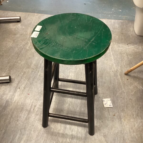 Vintage wooden stool with circular seat and four legs.
