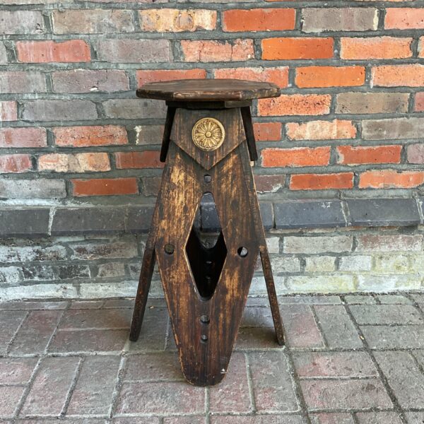 Vintage wooden trivet with tripod legs, rustic folk art.