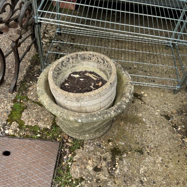 Two weathered stone garden planters on a patio.