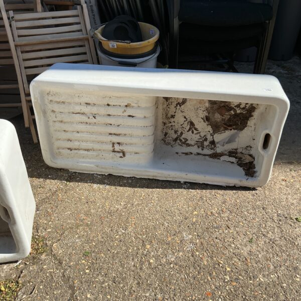 Large white Belfast sink repurposed as a garden planter.