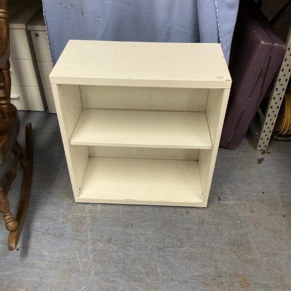 Small white bookcase for storage and display.