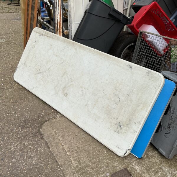 White folding table for camping and events, showing signs of wear.