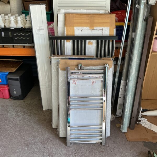 White ladder and panel radiators stacked for sale.