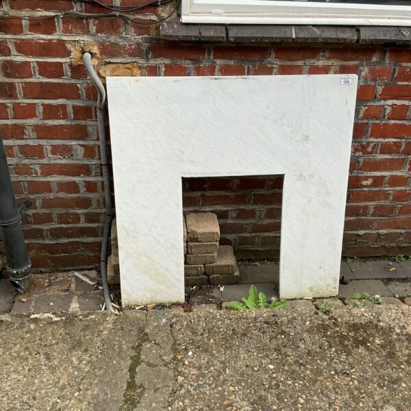 White marble fire surround with shaped opening for a fireplace.