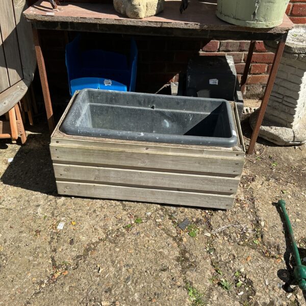 Rustic wooden plant trough for garden display.