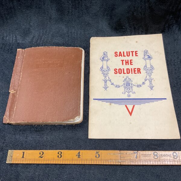 Vintage WWII raid spotter and cookbook books on a dark surface.