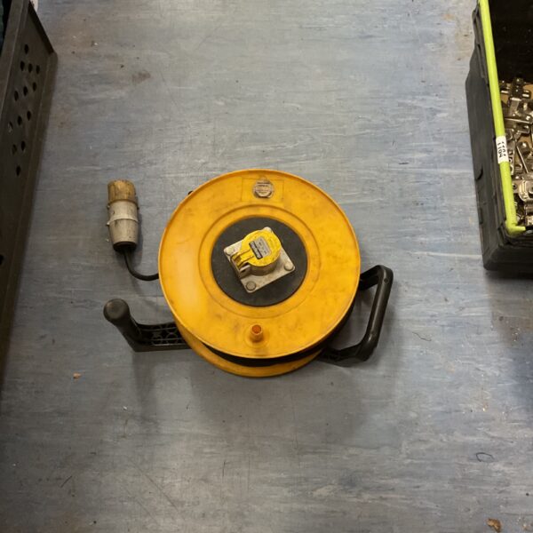 Yellow industrial retractable cable reel for workshop use.
