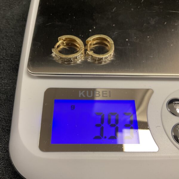Pair of 14ct gold hoop earrings on a scale.
