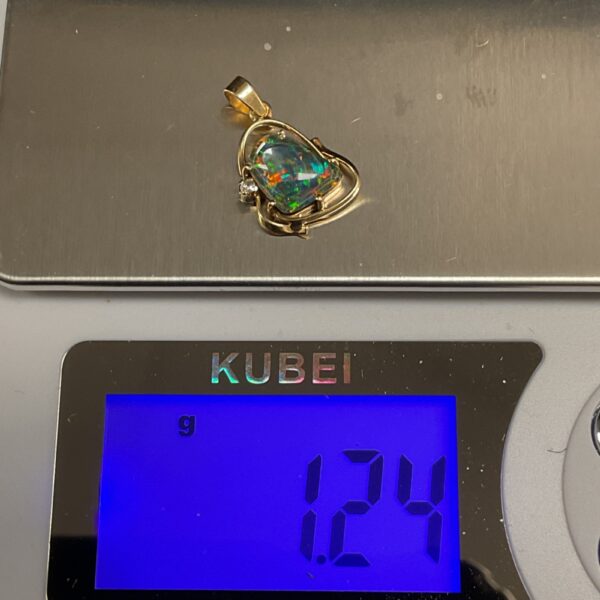 Close-up of a 14ct gold opal pendant with a colourful stone.