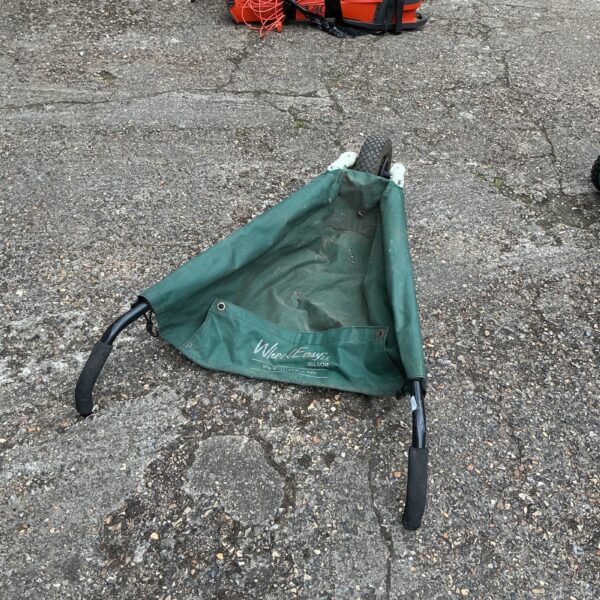 Blue and black Allsops folding wheelbarrow in a garden setting.