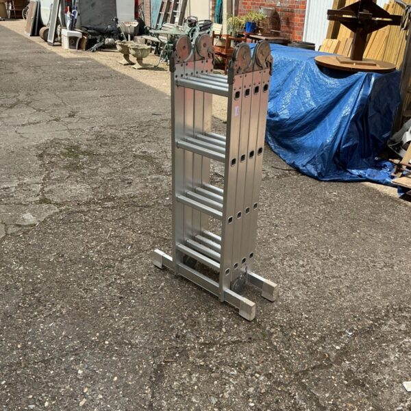 Silver aluminium folding ladder standing outdoors on a paved surface.