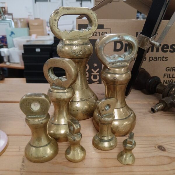 Set of four antique brass bell weights on a surface.