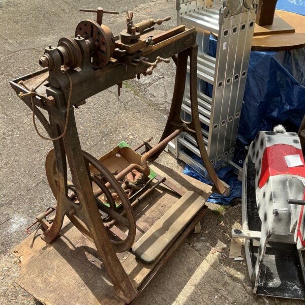 Antique lathe in a workshop setting, showing heavy duty metal construction.