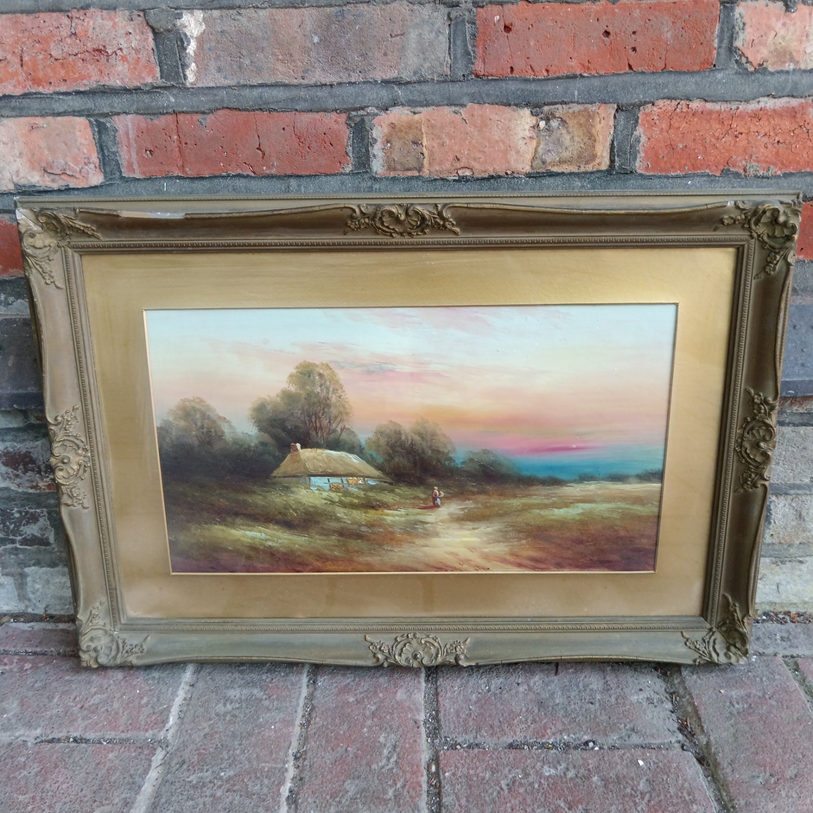 Antique oil painting of a country cottage with a gilt frame.