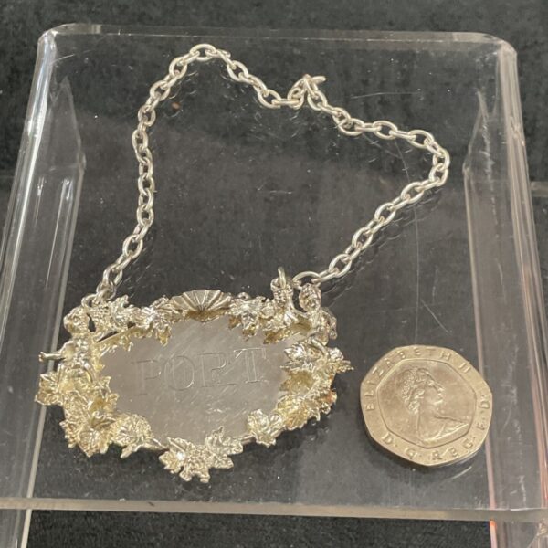 Antique sterling silver port decanter label with floral design.