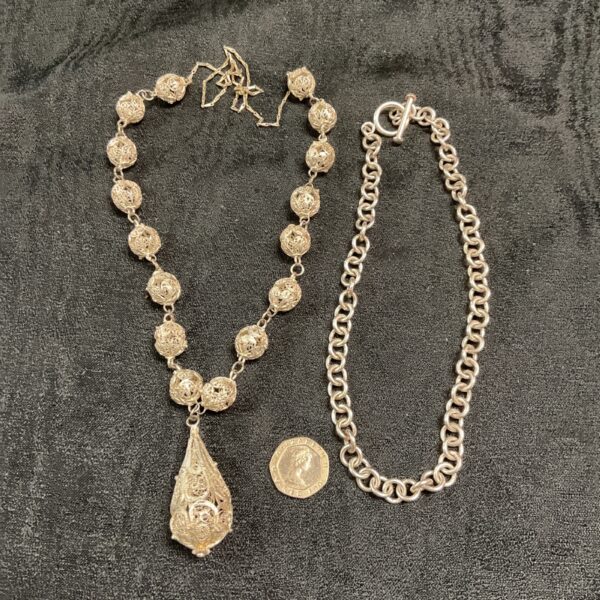 Antique silver watch chain necklace with intricate filligree pendant.