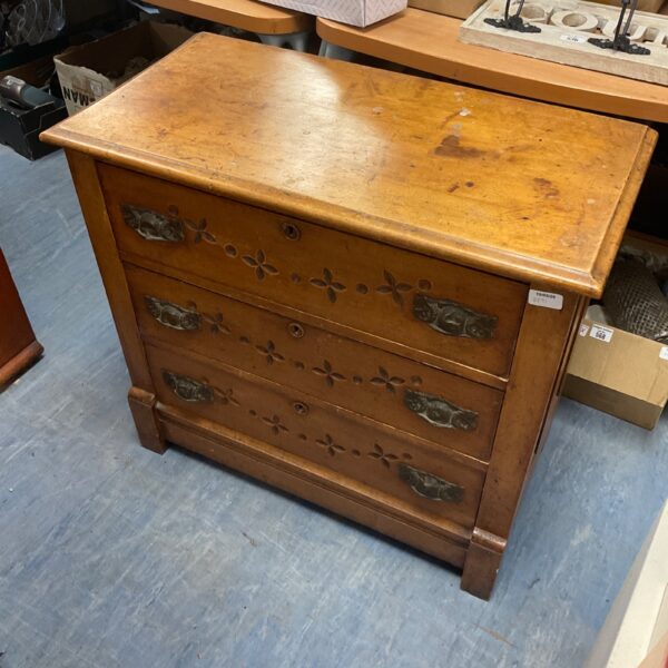 Antique Arts and Crafts chest of drawers with carved floral details.