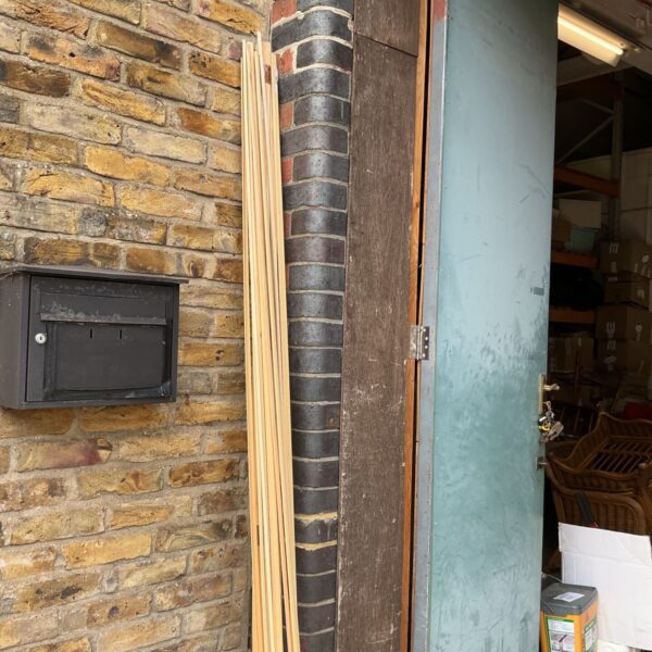 Quantity of wooden beading strips leaning against a door.