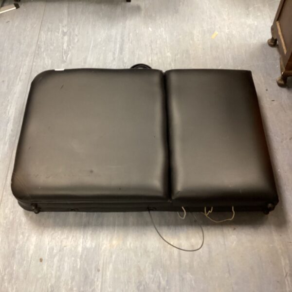 Black folding massage bed for spa treatments and therapy.