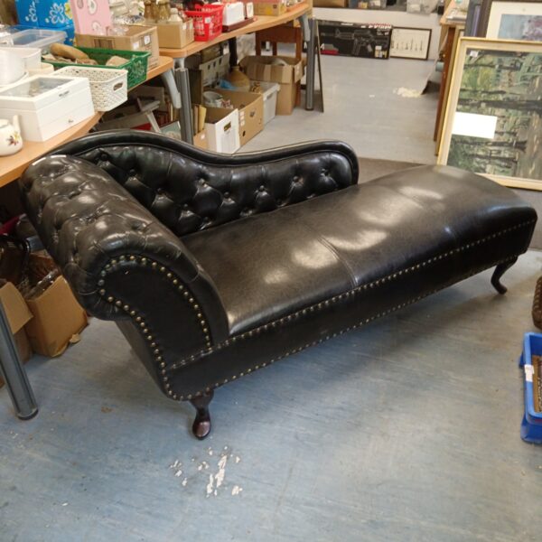 Elegant black leather chaise lounge with button tufting.