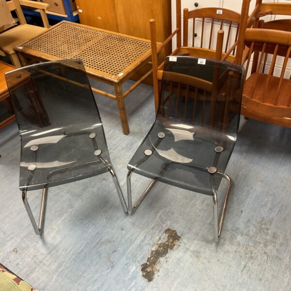 Pair of black polycarbonate chairs with chrome legs.