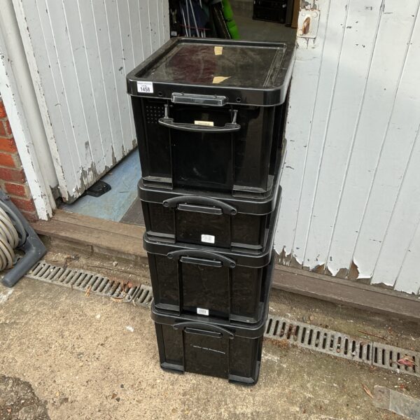 Lot of four black plastic storage boxes for household organisation.