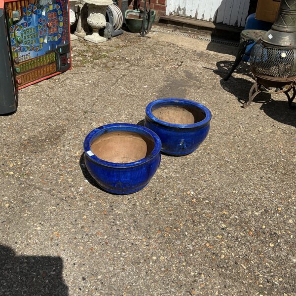 Vibrant blue glazed garden planters in an outdoor setting.