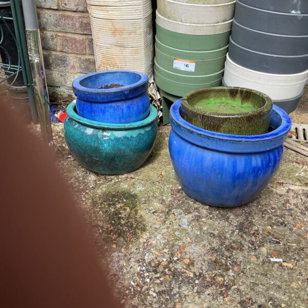 Four blue glazed terracotta garden pots displayed outdoors.