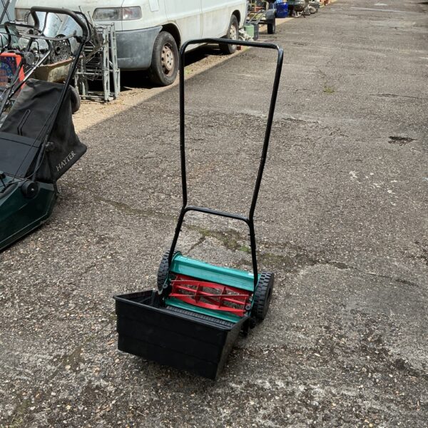 Vintage Bosch push lawn mower in a garden setting.