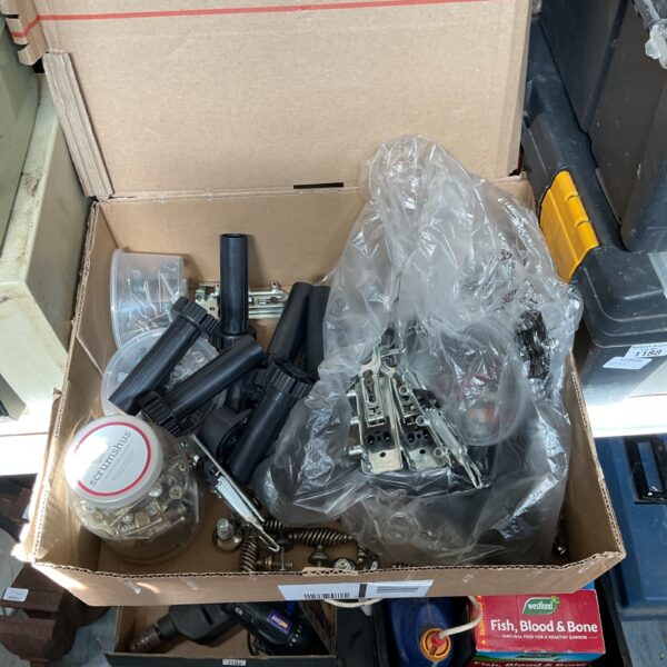 Box of assorted cabinet hardware including legs, handles, and hinges.