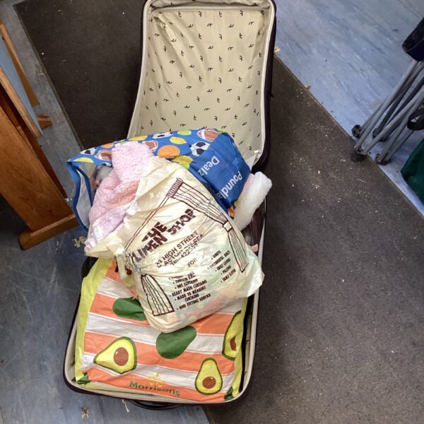 Vintage suitcase filled with a children’s clothes bundle.