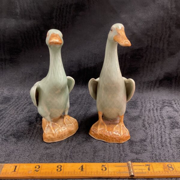 Pair of vintage Chinese porcelain duck ornaments on display.