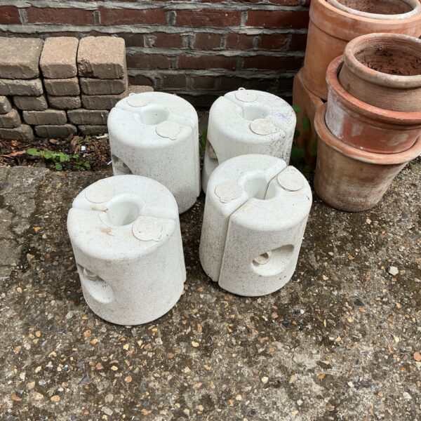 Four grey concrete gazebo weights for outdoor stability.