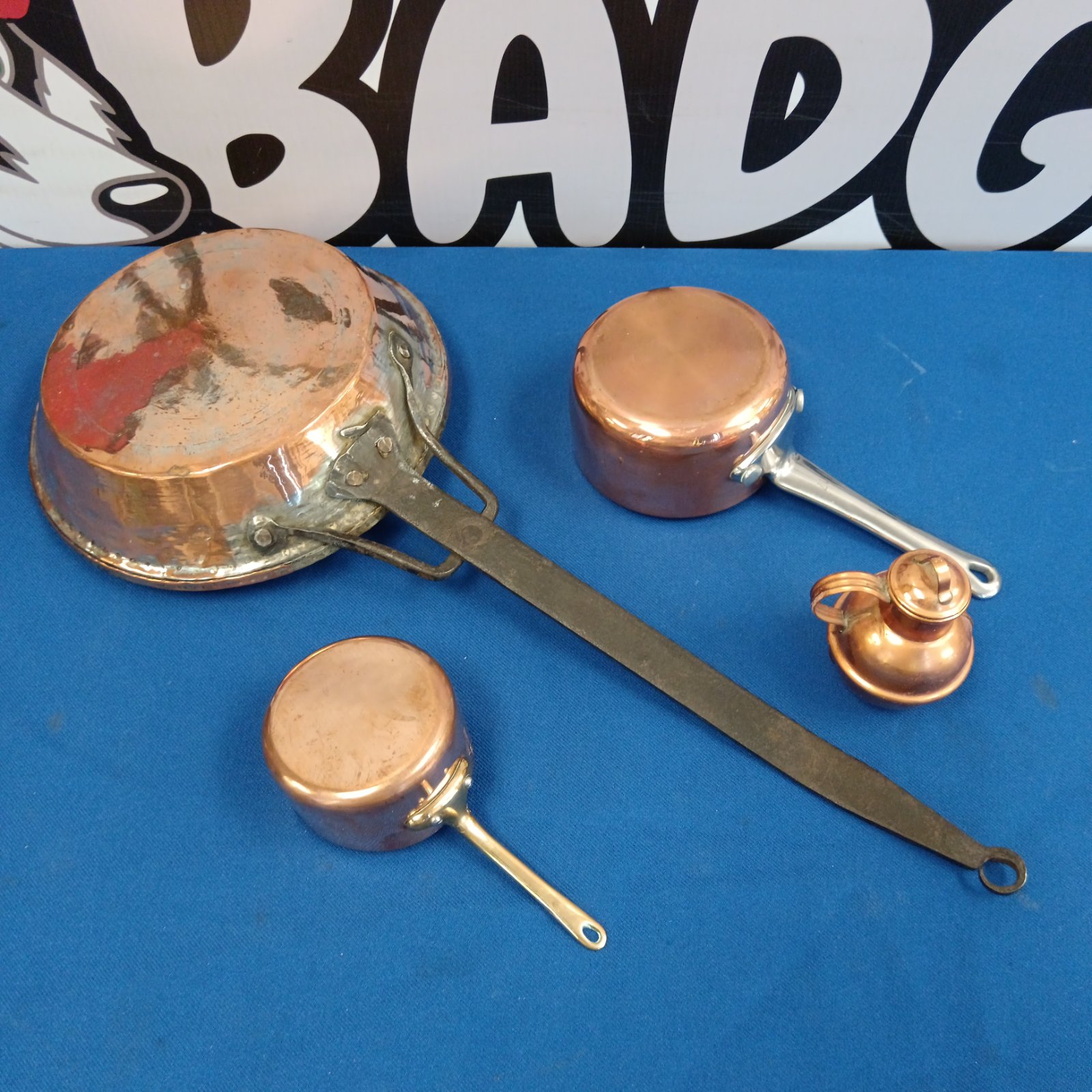 Vintage copper cooking pans and a miniature milk urn on display.