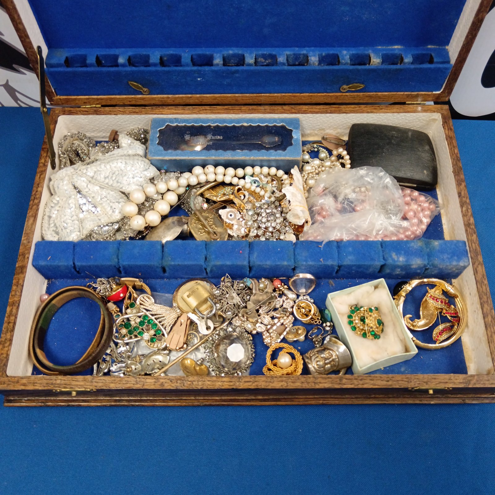 Vintage costume jewellery lot displayed in a cutlery box.
