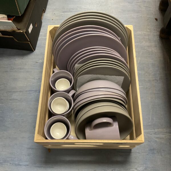Crate of pastel Dunelm plates, bowls, and mugs.