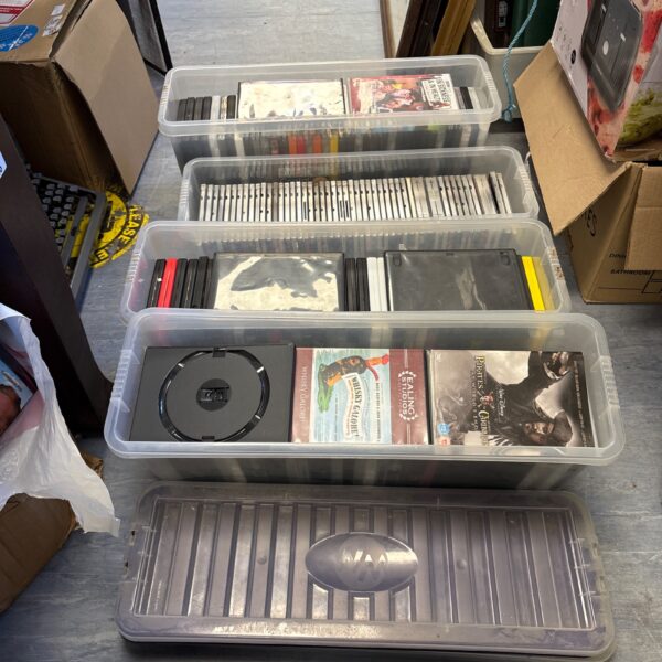 Mixed DVD and CD lot in clear storage boxes.