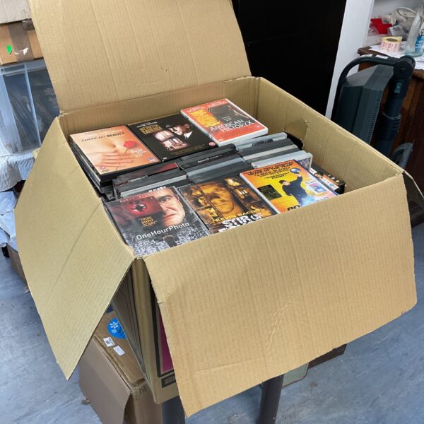 Full cardboard box of assorted DVDs for home movie entertainment.